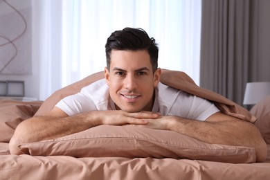 Photo of Man lying in comfortable bed with beige linens