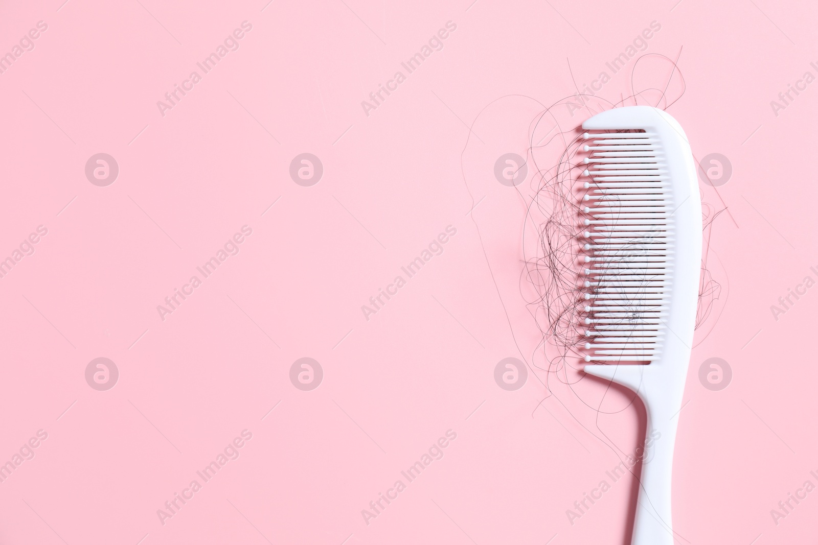 Photo of Comb with lost hair on pink background, top view. Space for text