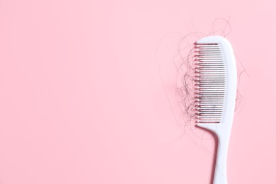 Photo of Comb with lost hair on pink background, top view. Space for text