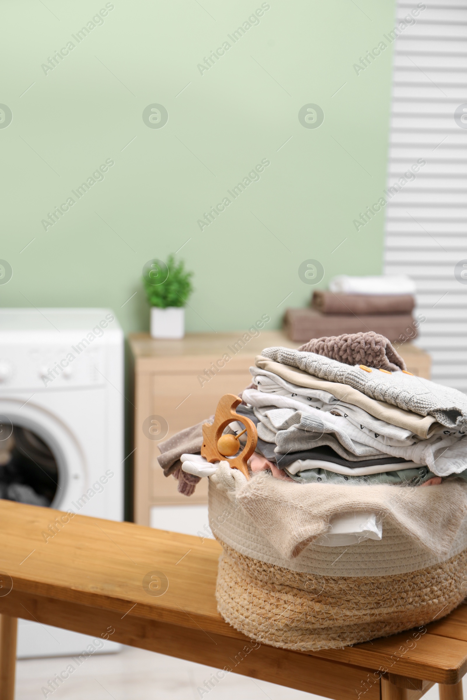 Photo of Laundry basket with baby clothes and toy on table in bathroom