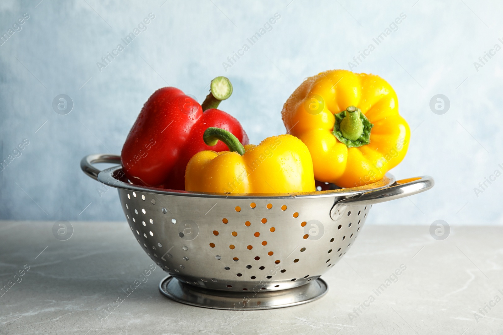 Photo of Colander with ripe paprika peppers on table