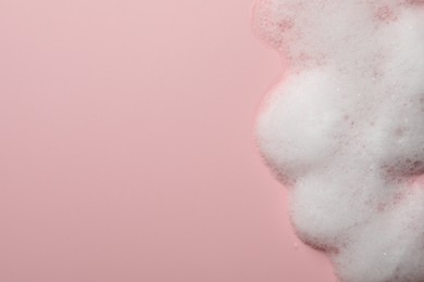 Fluffy soap foam on pink background, top view. Space for text