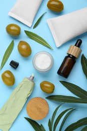 Photo of Cosmetic products with olive essential oil light turquoise background, flat lay