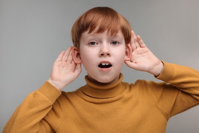 Photo of Little boy with hearing problem on grey background