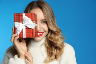 Photo of Happy young woman with christmas gift on light blue background