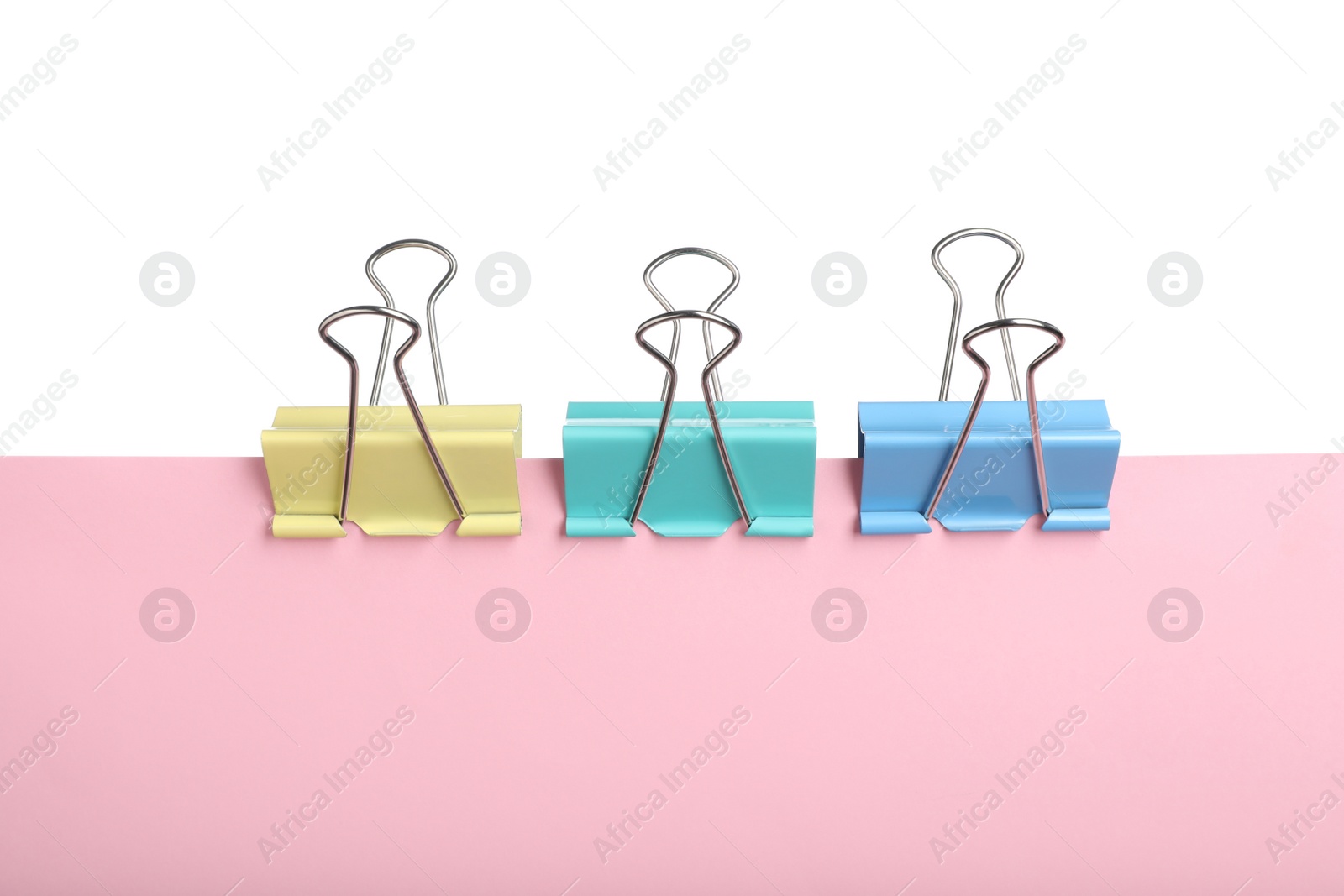 Photo of Pink paper with colorful binder clip isolated on white
