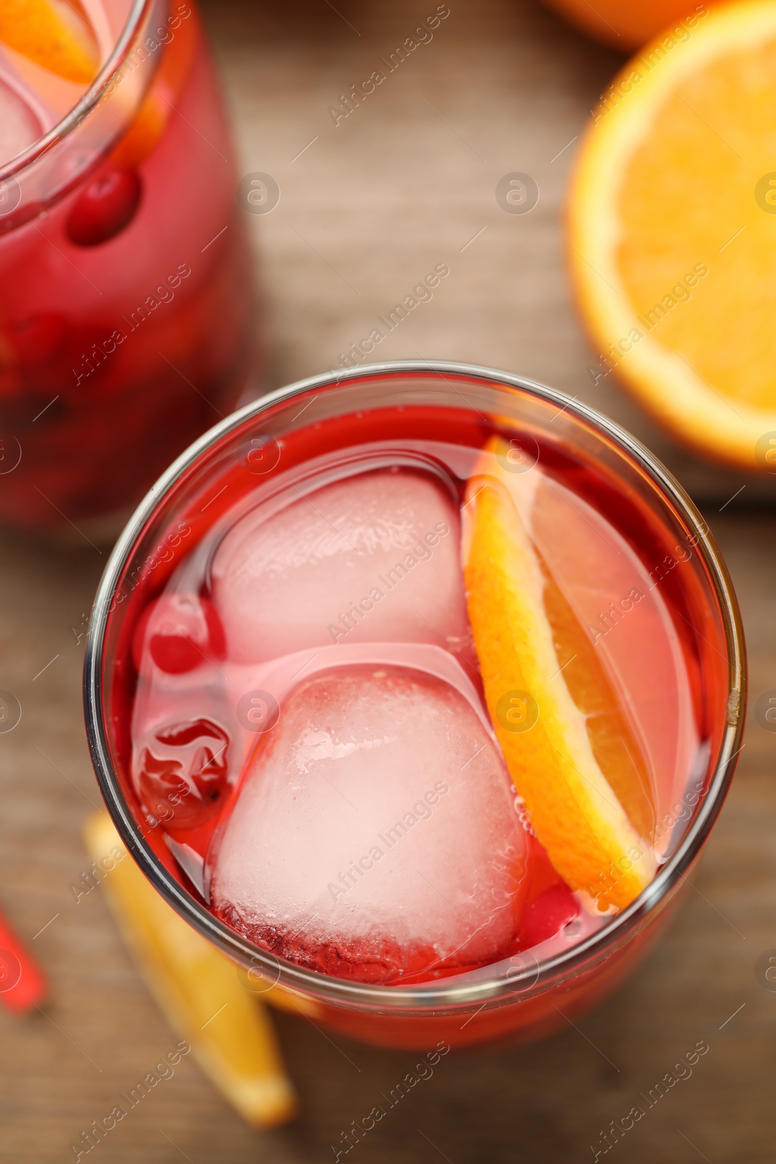 Photo of Tasty cranberry cocktail with ice cubes and orange in glasses on table, flat lay