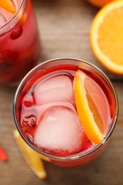 Tasty cranberry cocktail with ice cubes and orange in glasses on table, flat lay