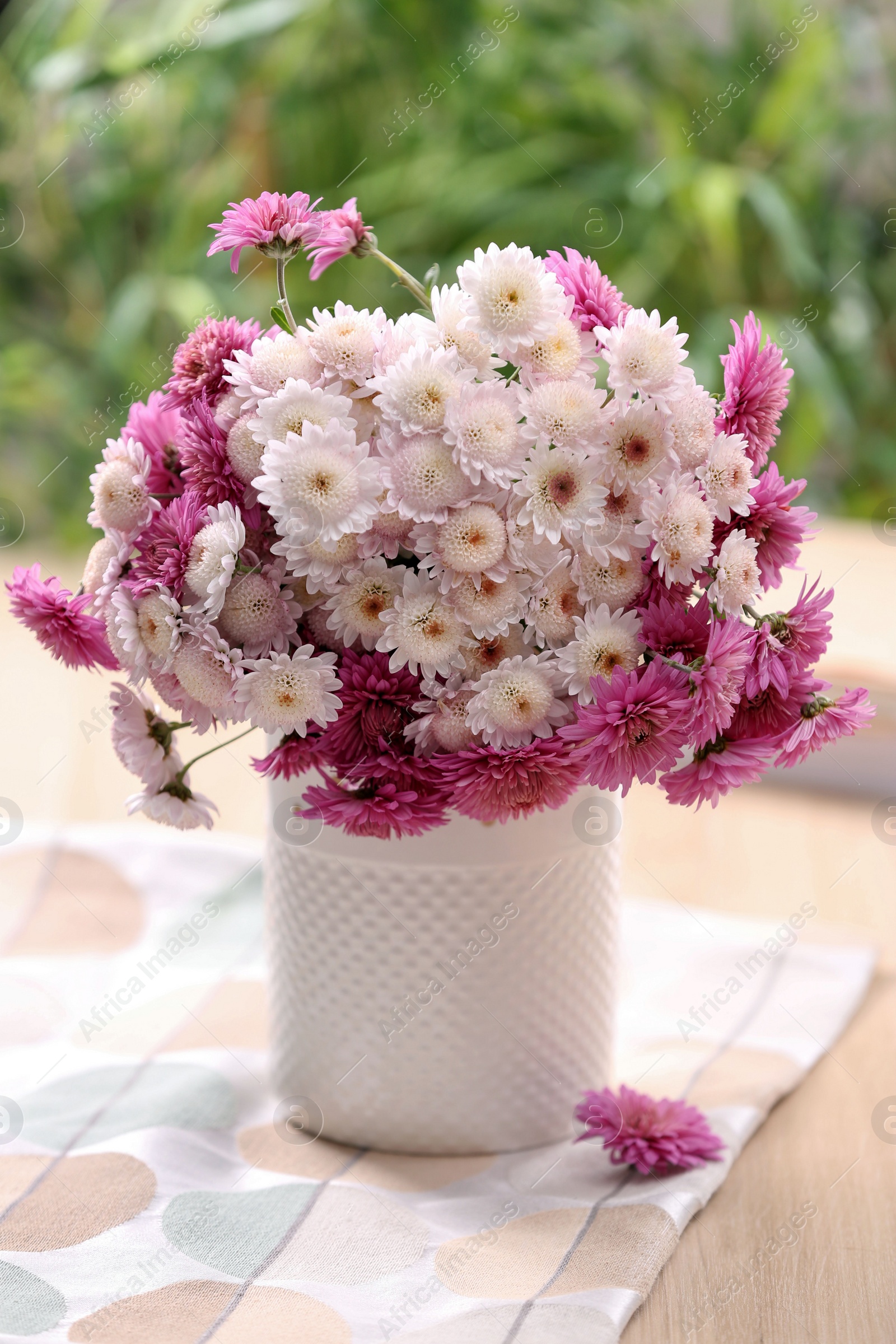 Photo of Vase with beautiful bouquet, books and cloth on wooden table