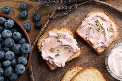 Photo of Tasty sandwiches with cream cheese, thyme and blueberries on wooden table, flat lay