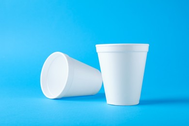 White styrofoam cups on light blue background
