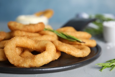 Fried onion rings served on grey table, closeup
