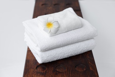 Photo of Stacked bath towels and beautiful flower on tub tray