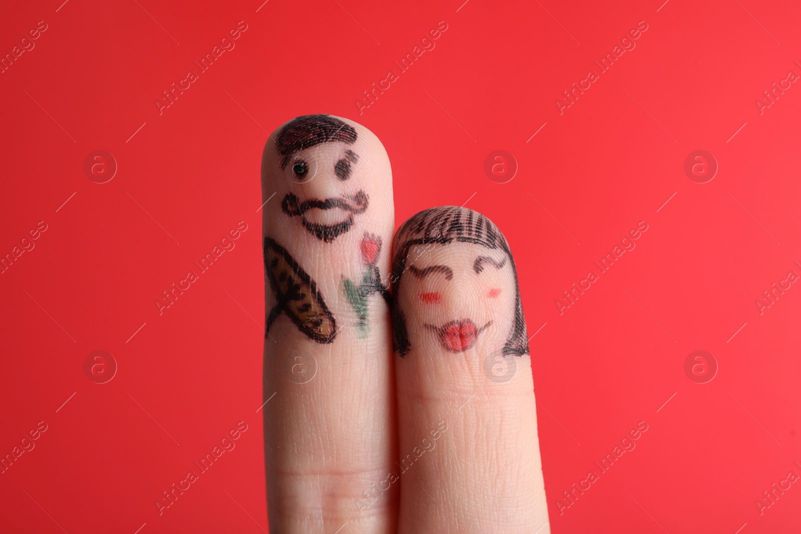 Photo of Two fingers with drawings of happy faces on red background. Spending time together