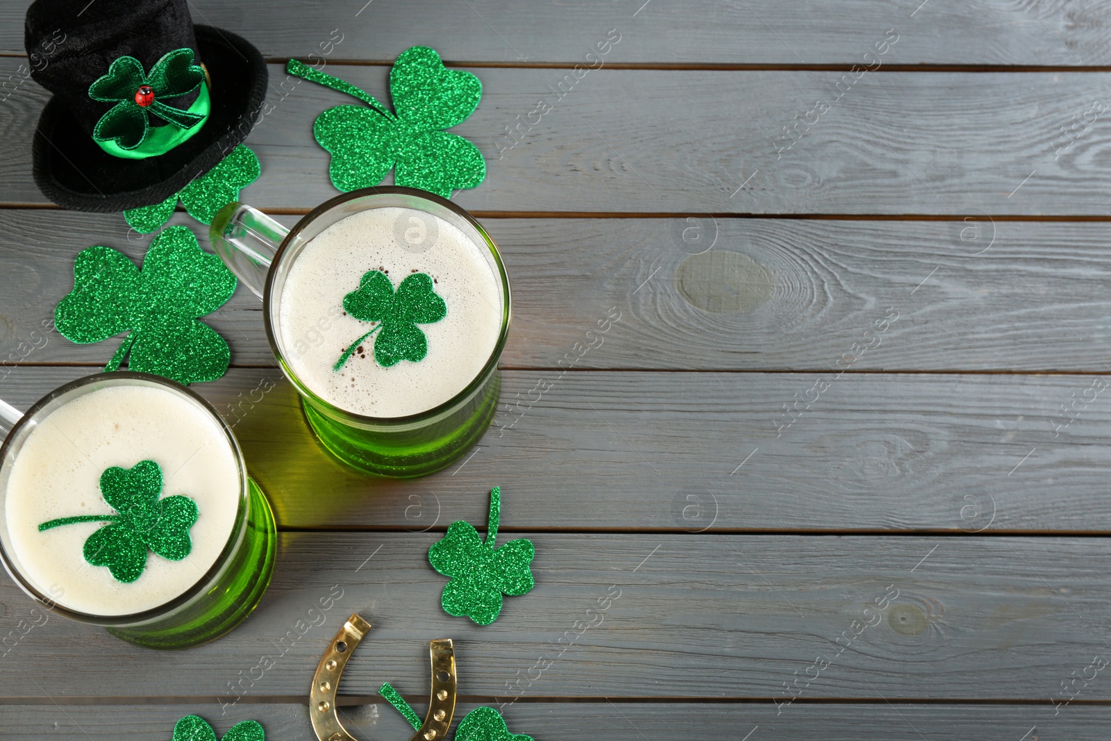 Photo of Flat lay composition with green beer and clover leaves on grey wooden table, space for text. St. Patrick's Day celebration