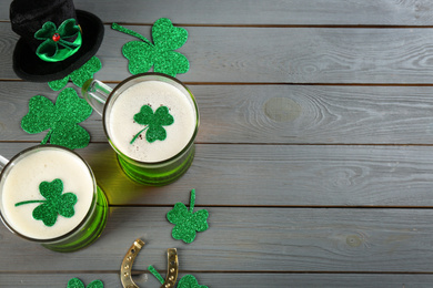 Photo of Flat lay composition with green beer and clover leaves on grey wooden table, space for text. St. Patrick's Day celebration