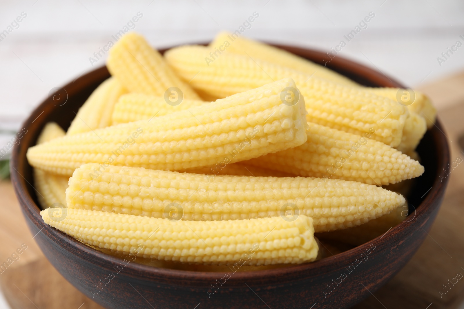 Photo of Tasty fresh yellow baby corns in bowl on table, closeup