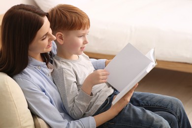 Mother reading book with her child at home