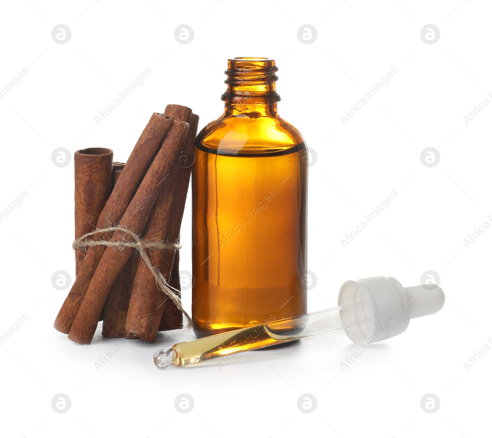 Photo of Bottle with cinnamon oil and sticks on white background