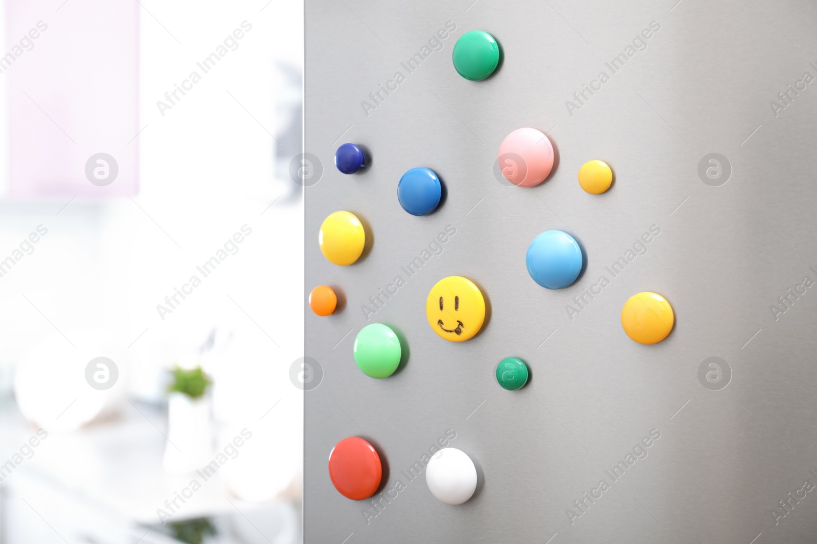 Photo of Colorful magnets on refrigerator door in kitchen. Space for text