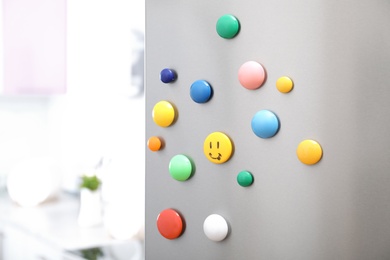 Photo of Colorful magnets on refrigerator door in kitchen. Space for text