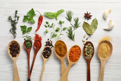 Photo of Spoons with different spices and herbs on white wooden table, flat lay