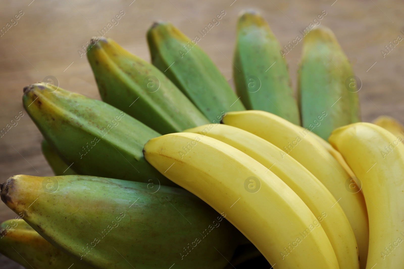 Photo of Bunches of tasty bananas on wooden table, closeup