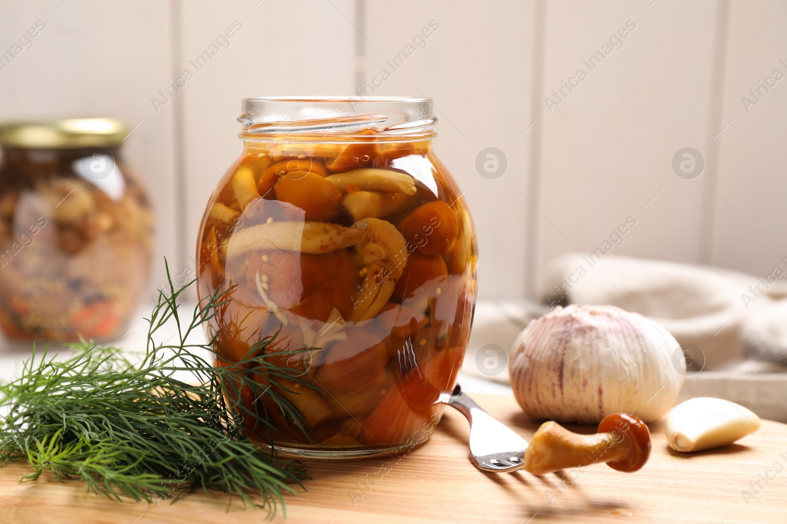Photo of Delicious marinated mushrooms in glass jar on table