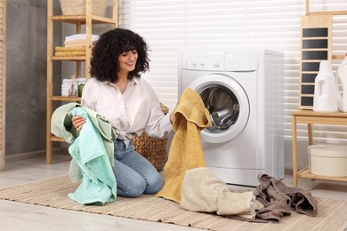 Woman with laundry near washing machine indoors