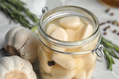 Photo of Jar of pickled garlic on table, closeup