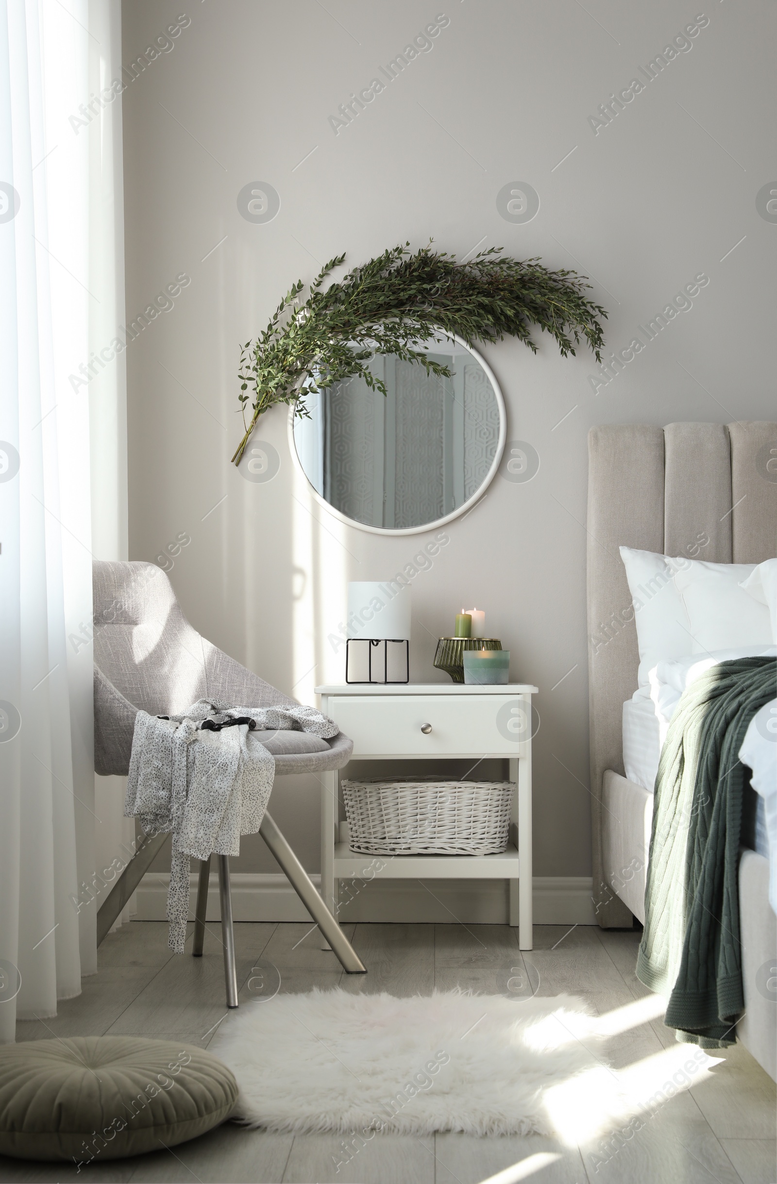 Photo of Stylish mirror decorated with green eucalyptus in bedroom