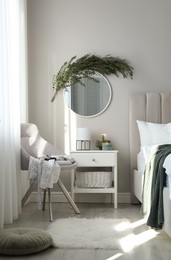 Stylish mirror decorated with green eucalyptus in bedroom