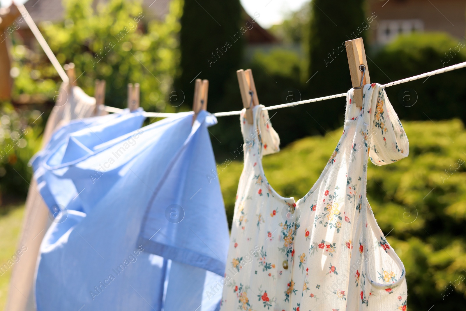 Photo of Clean clothes hanging on washing line in garden. Drying laundry