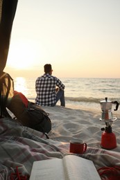Man enjoying sunset on beach, view from camping tent