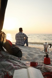 Photo of Man enjoying sunset on beach, view from camping tent