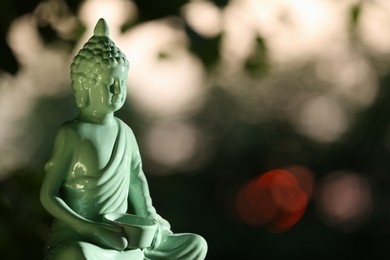 Photo of Decorative Buddha statue on blurred background outdoors. Space for text