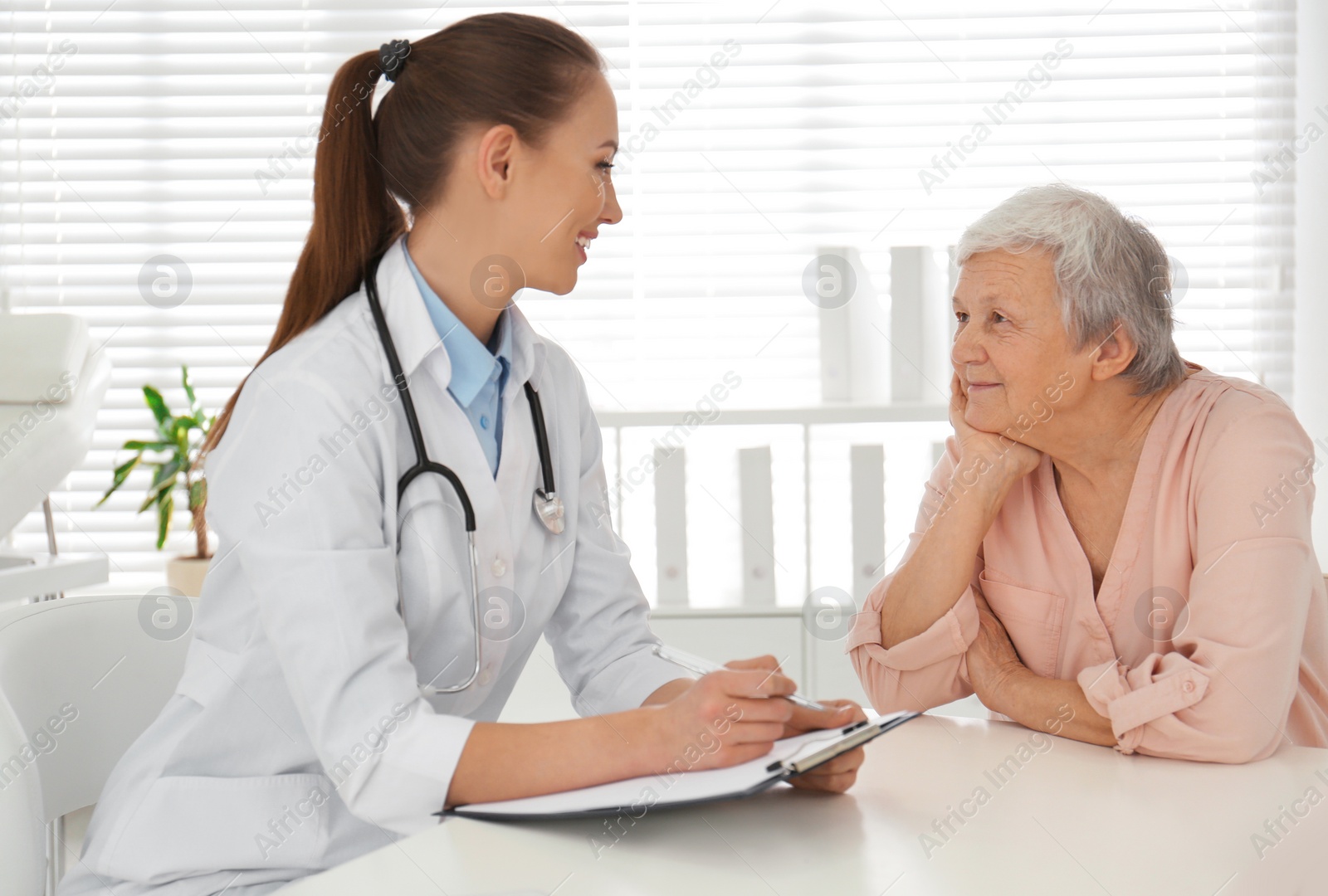 Photo of Doctor examining senior patient in modern office