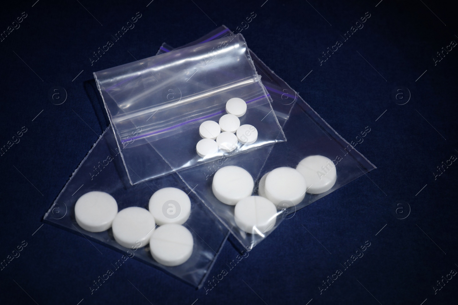 Photo of Ecstasy pills in plastic bags on color background