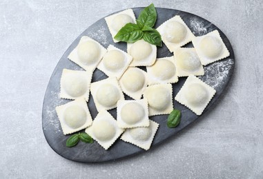 Homemade uncooked ravioli on grey table, top view