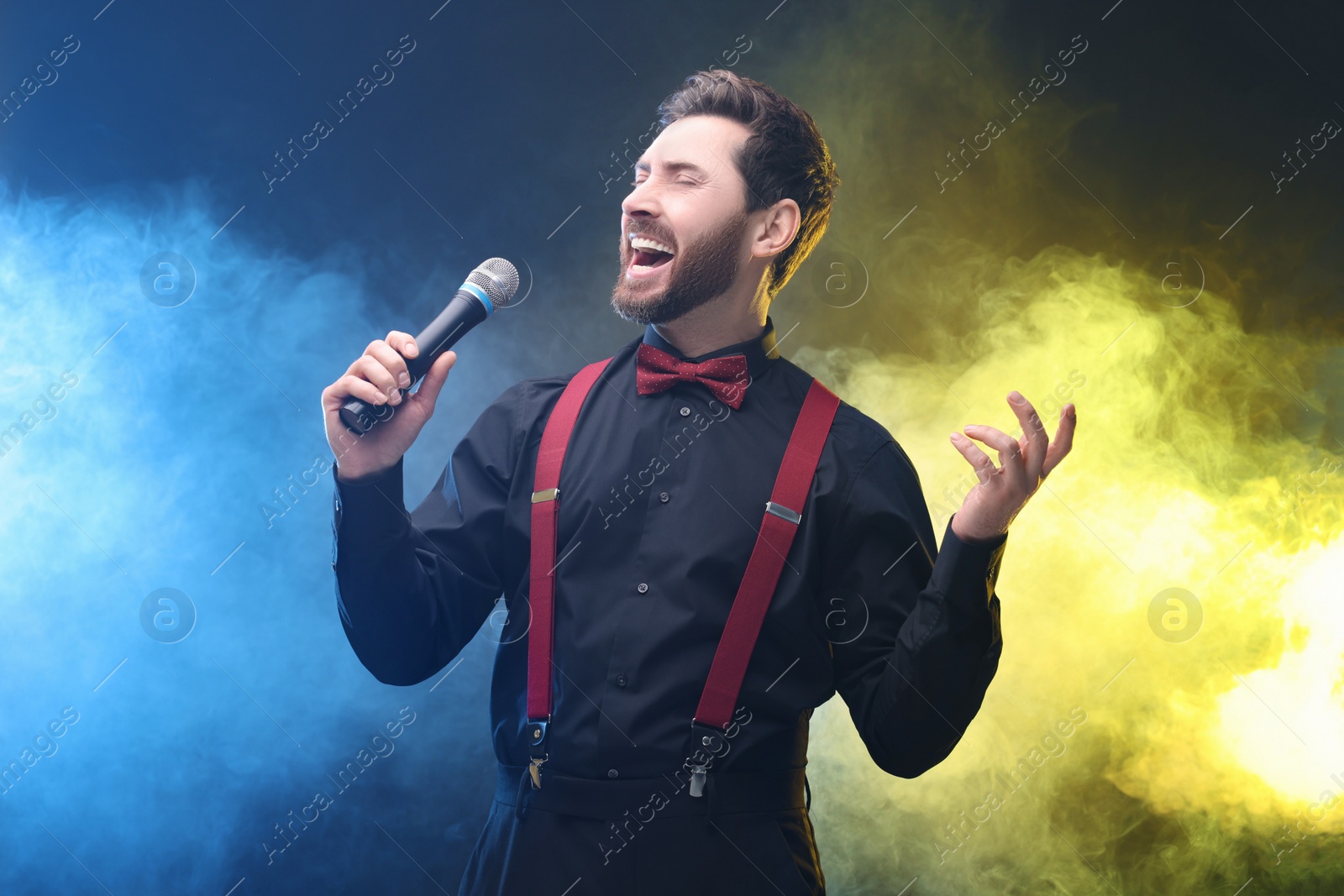 Photo of Emotional man with microphone singing in color lights