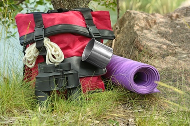 Photo of Backpack and camping equipment on grass near tree in wilderness