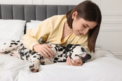 Beautiful woman with her adorable Dalmatian dog on bed at home. Lovely pet