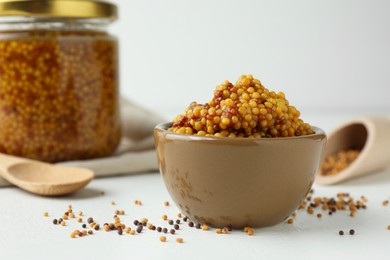 Photo of Fresh whole grain mustard in bowl and dry seeds on white table