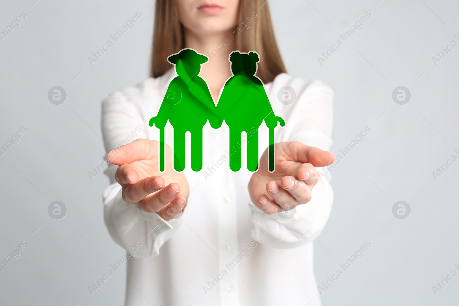 Image of Woman demonstrating image of elderly couple on light background, closeup. Retirement concept