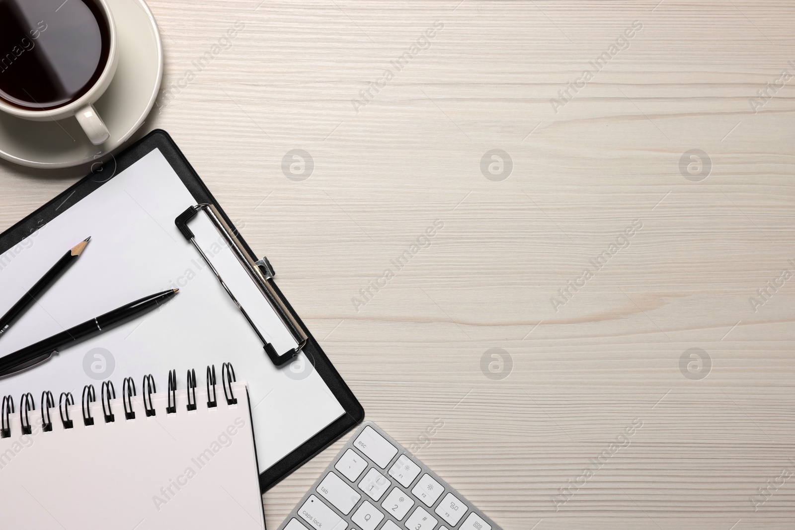 Photo of Home office. Coffee, computer keyboard and stationery on white wooden desk, flat lay. Space for text