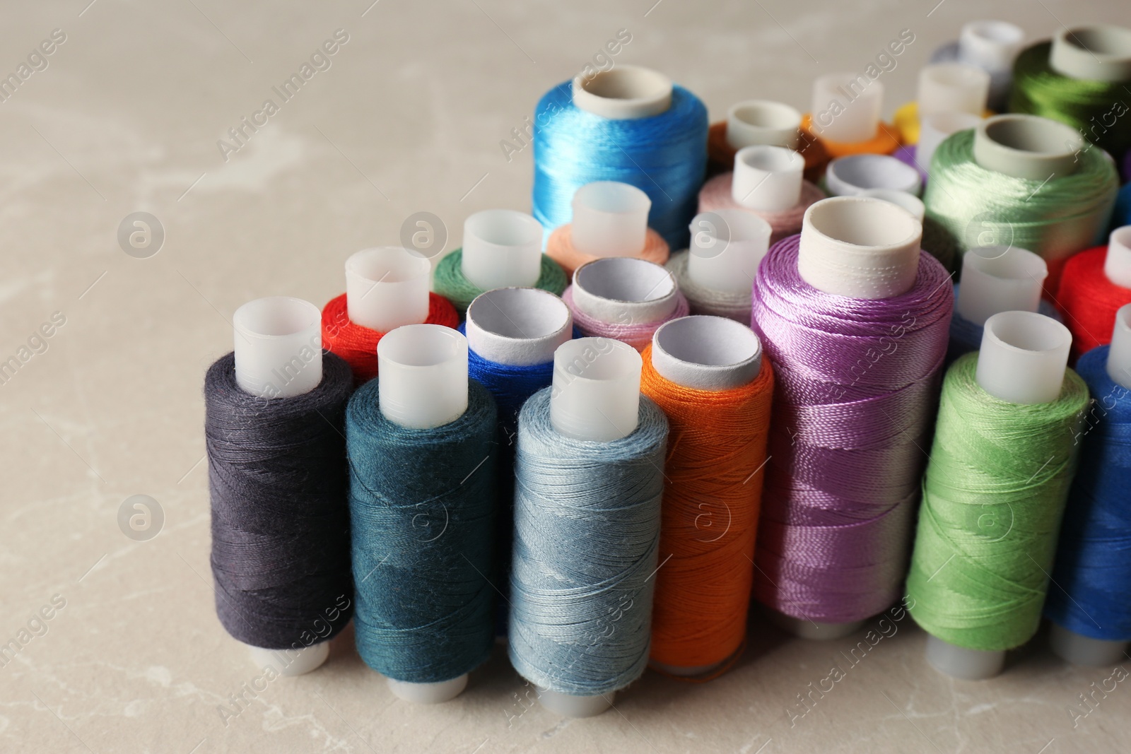 Photo of Set of color sewing threads on light grey table