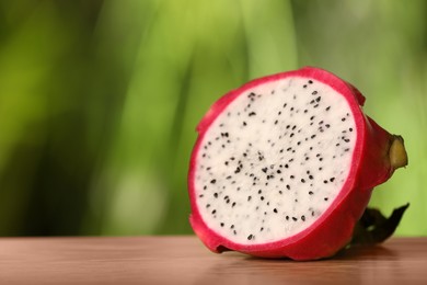 Delicious cut dragon fruit (pitahaya) on wooden table. Space for text