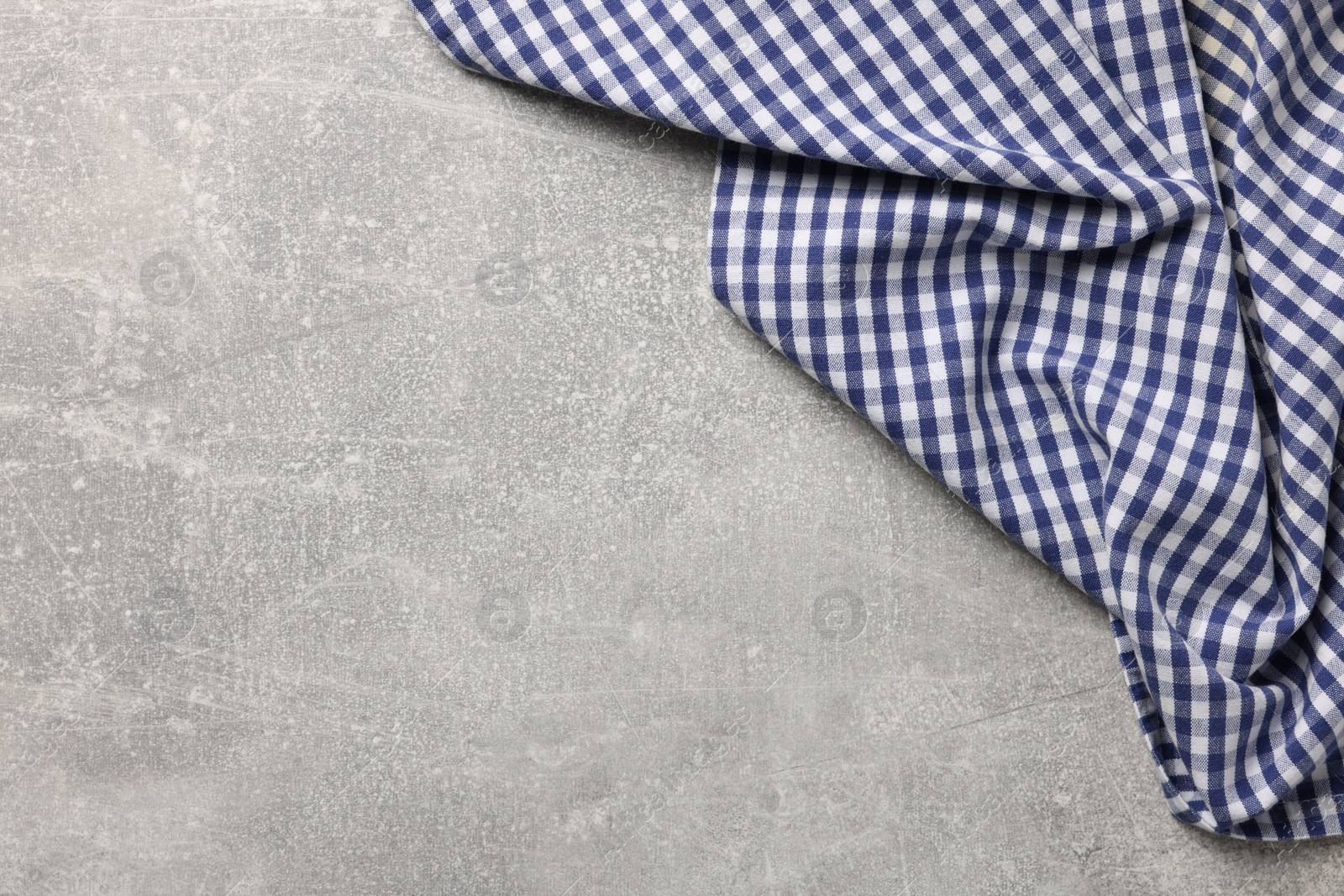 Photo of Blue checkered tablecloth on light gray textured table, top view. Space for text