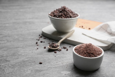 Ground black salt in bowl on grey table. Space for text