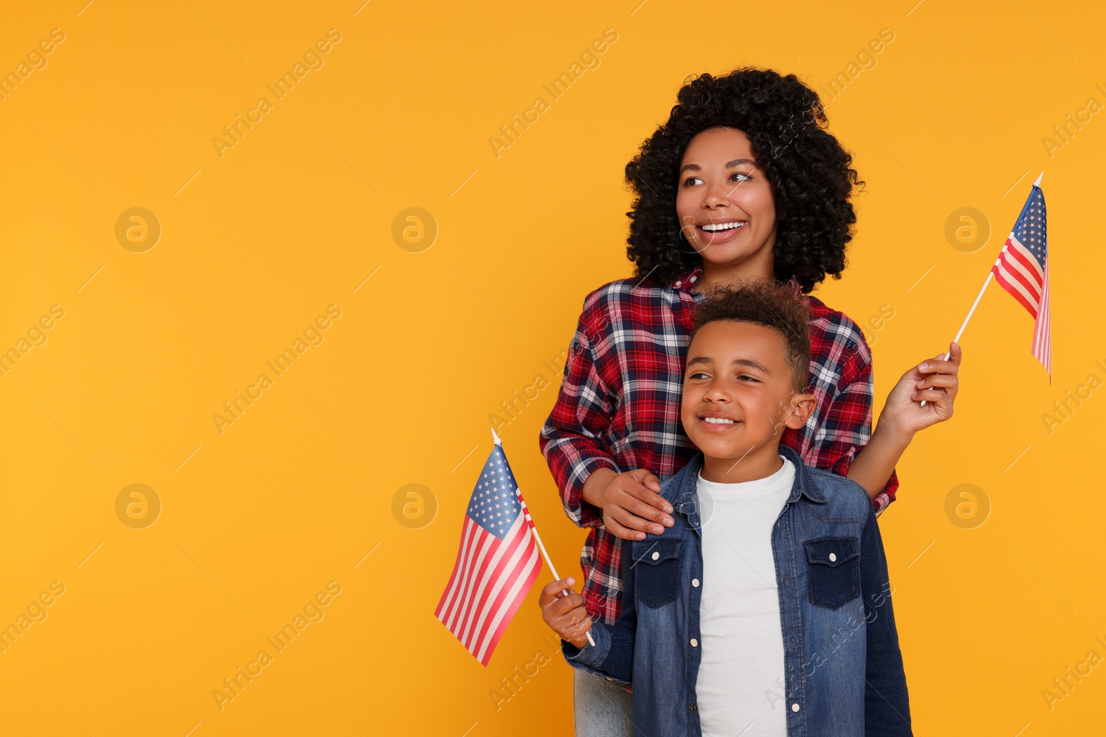 Photo of 4th of July - Independence Day of USA. Happy woman and her son with American flags on yellow background, space for text
